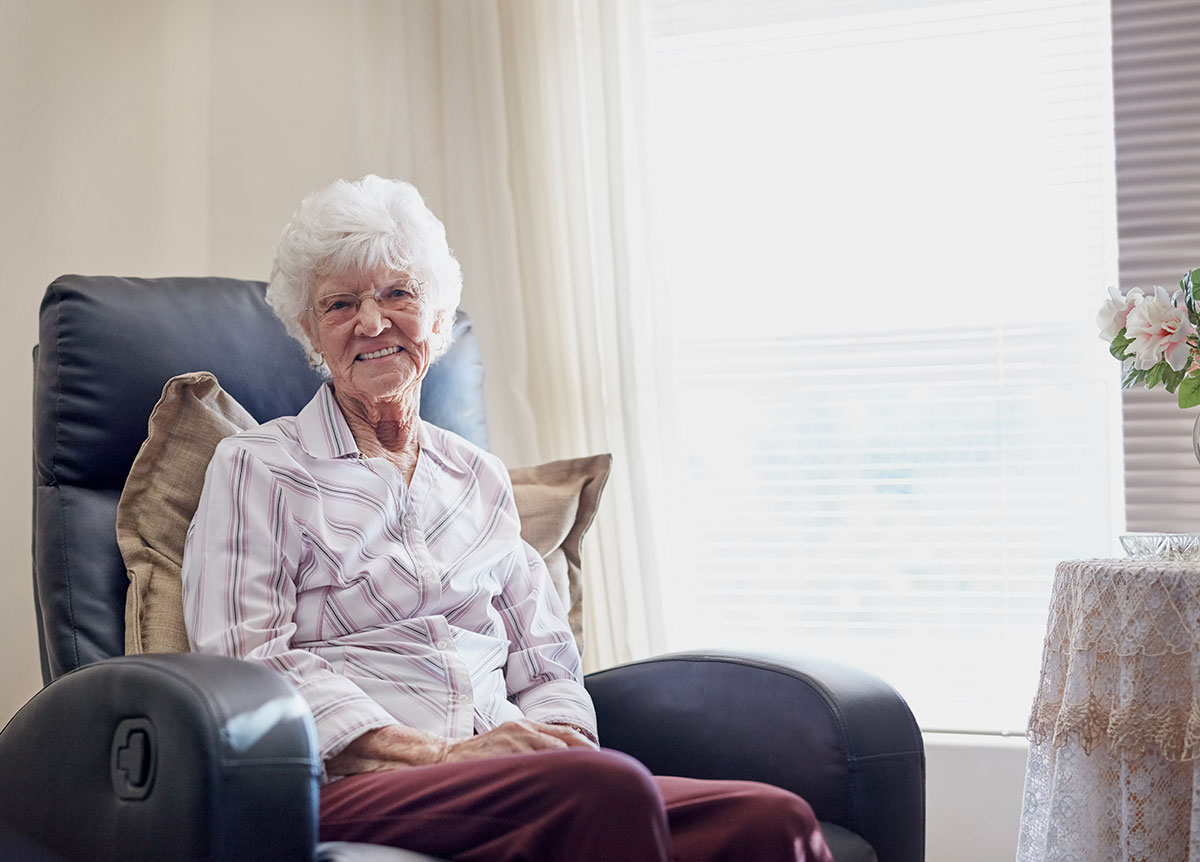 elderly lady sitting by window in assisted living home
